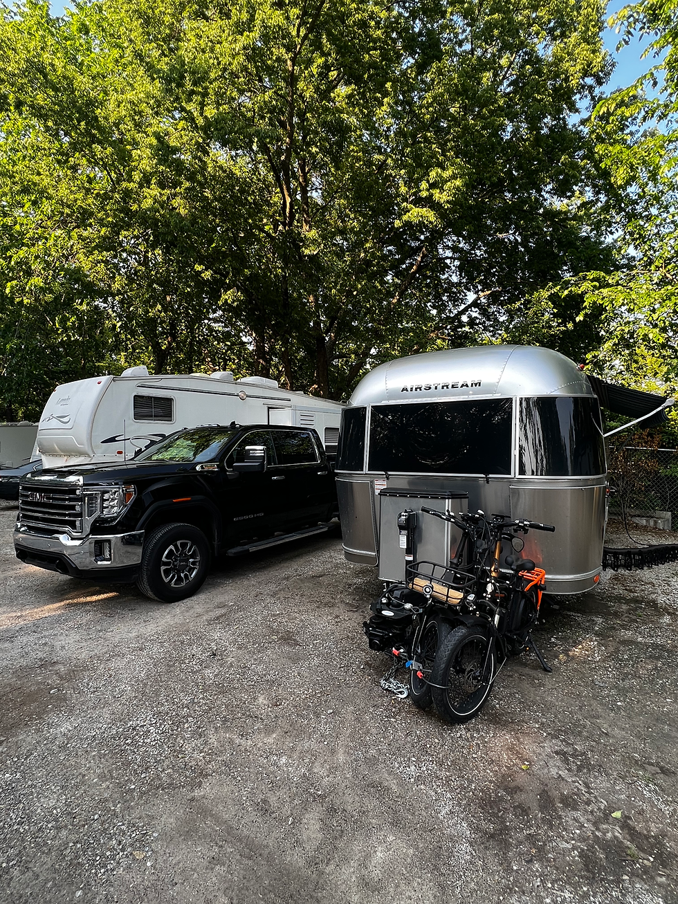 An Airstream trailer and black GMC truck are parked closely next to another RV