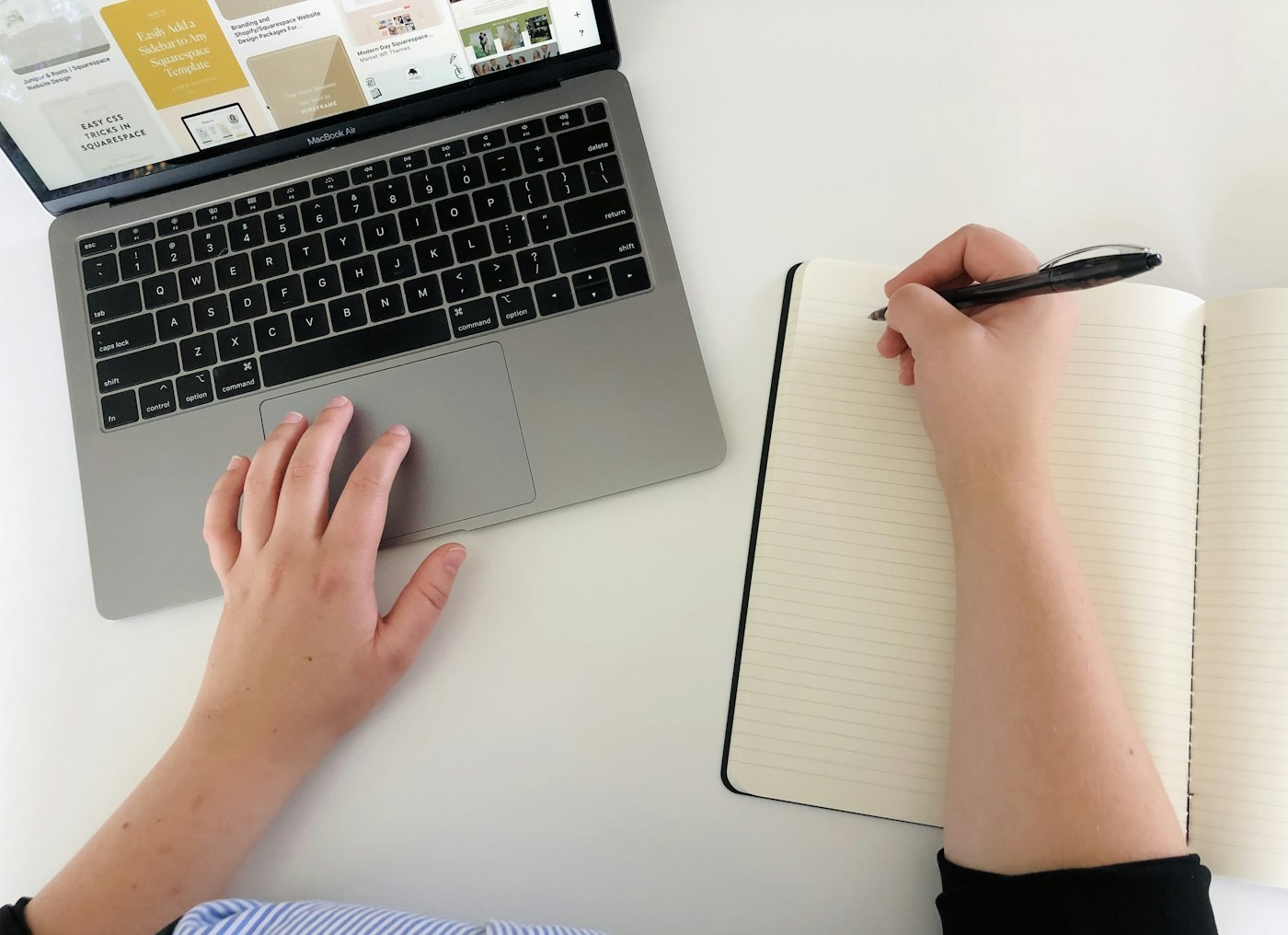Real editorial photograph of person working at laptop and writing in notebook. Cover for The Digital Sunset Experiment