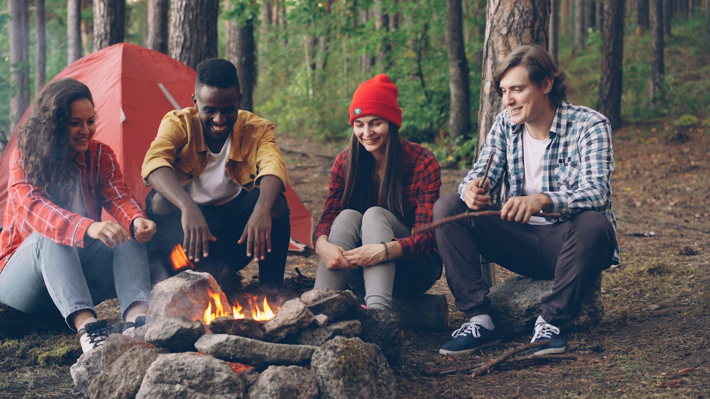 Real editorial photograph of outdoor campfire friendship. Cover for Low-Waste Camping as a Group Challenge