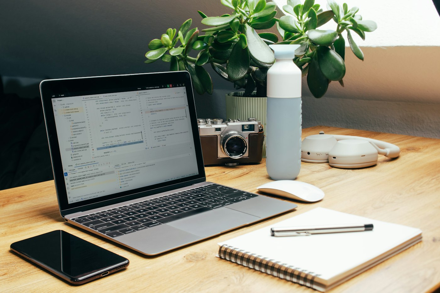 Real editorial photograph of laptop phone notebook and camera on desk. Cover for Wearables: Useful Feedback or Too Much Data?