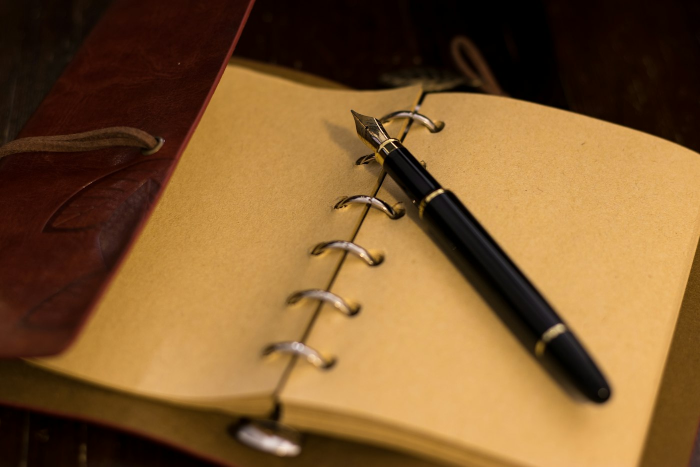 Real editorial photograph of a notebook and pen. Cover for Lucid Dreaming Without Chasing Control