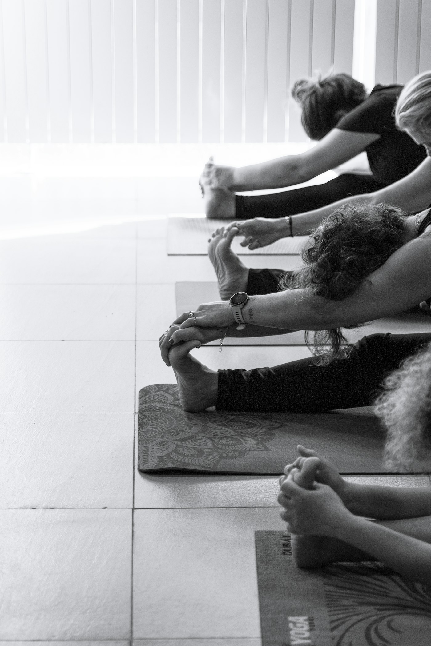 Real editorial photograph of group stretching on yoga mats in studio. Cover for Humming as a Quiet Body Practice