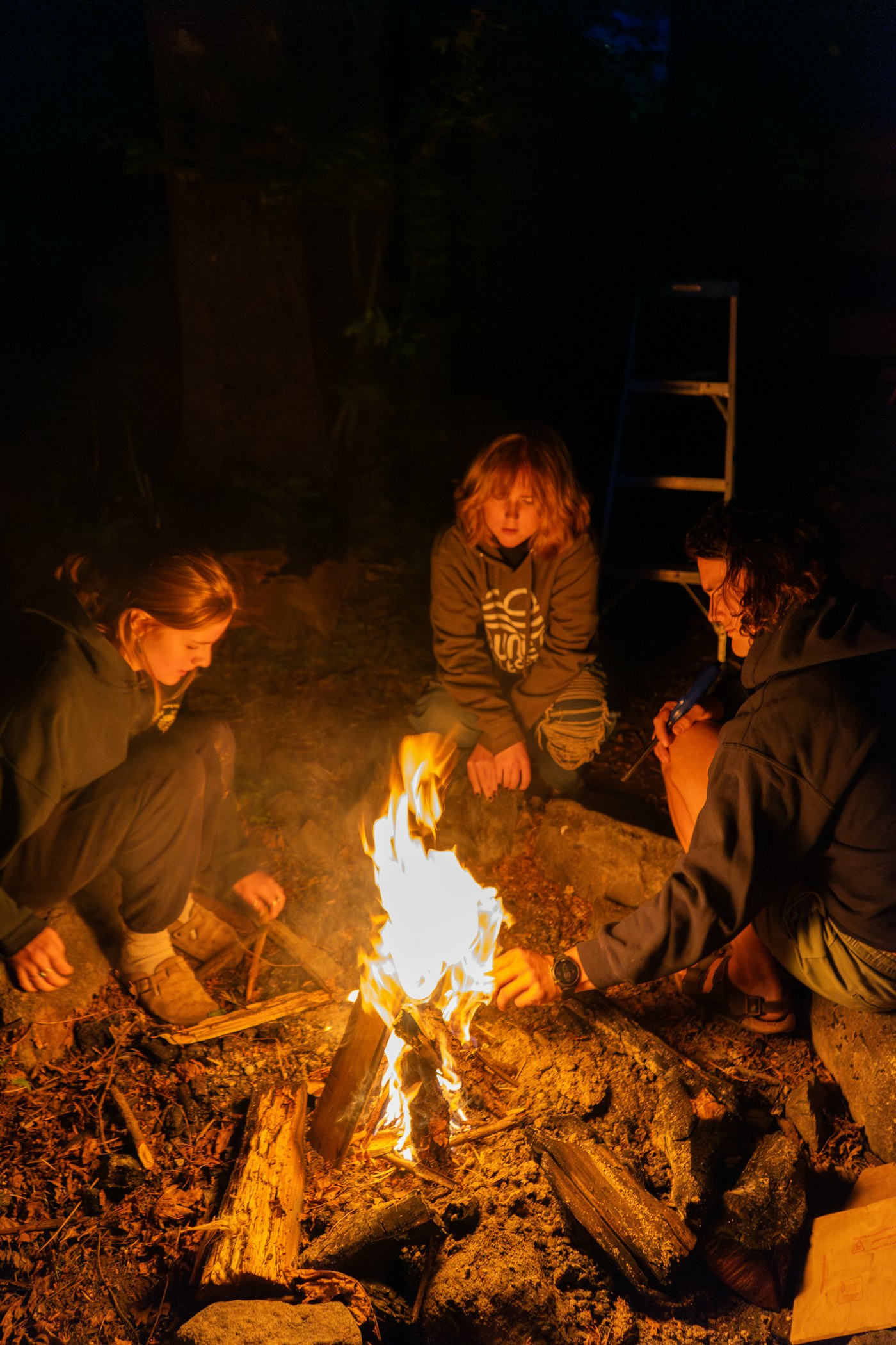 Real editorial photograph of warm campfire gathering at night. Cover for Disagreement Without Dividing the Circle