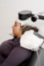 A patient receiving Transcranial Magnetic Stimulation (TMS) therapy with a specialized coil.