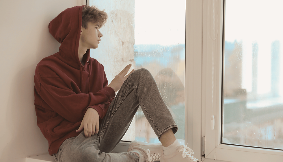 Teen sitting quietly in natural light, representing emotional exhaustion from masking.