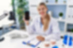 Beautiful dentist woman showing smartphone screen looking positive and happy standing and