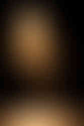 A solo contemporary dance performer under a warm spotlight, crouching or preparing to move.