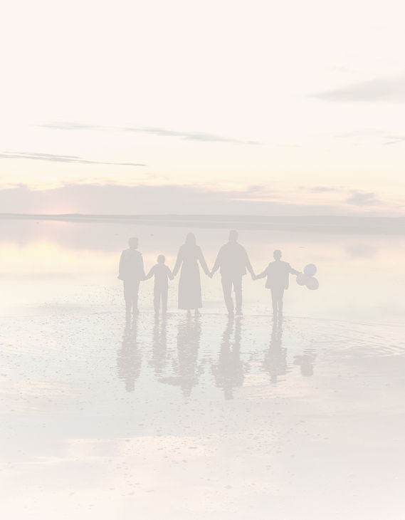 Family holding hands at sunset by the wa