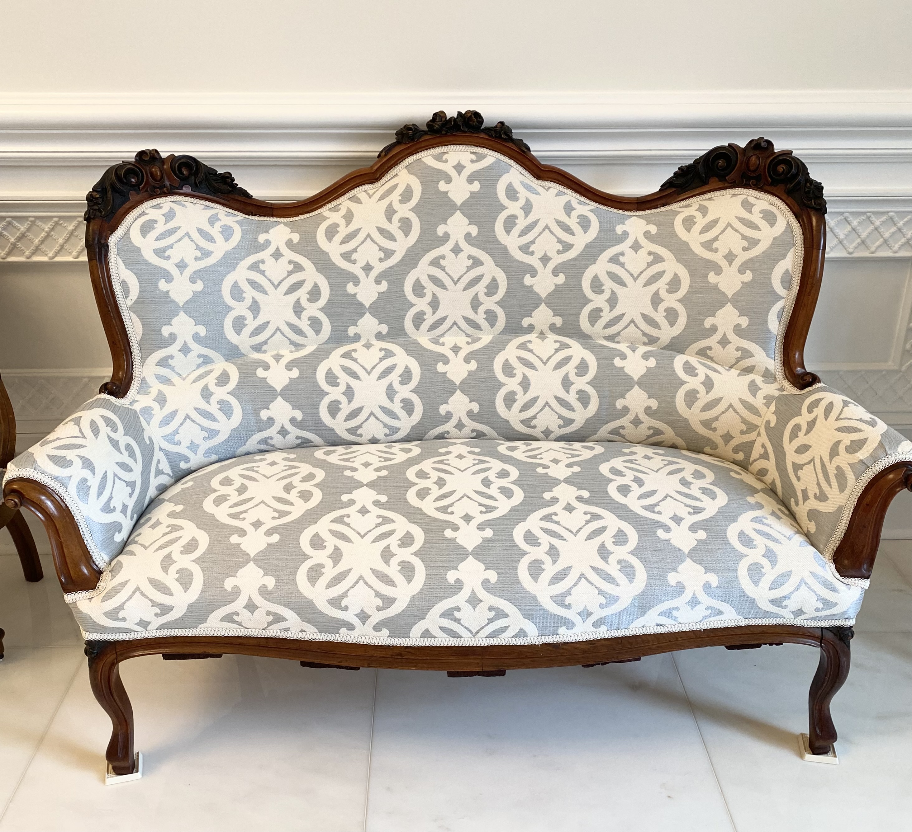 Antique wooden settee professionally reupholstered with light gray and white patterned fabric, showcasing custom upholstery craftsmanship