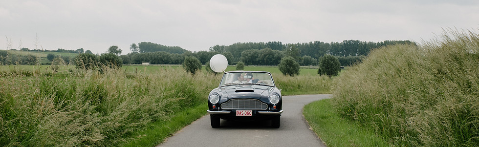 A romantic countryside drive in a classic black convertible, perfect for a timeless destination wedding getaway. 