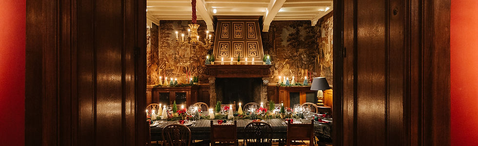 A wide shot of an elegant dining room, fully styled with holiday candles and garlands, ready for an intimate post-baptism gathering.