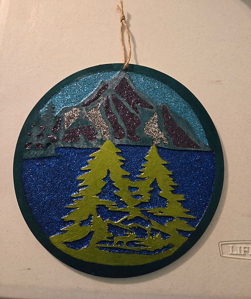 Mountain Lake | 8" round wood cutout finished with acrylic paint and glitter varnish | deep green, light greens, onyx, silver and blues | acrylic painting | mountain lake | lake side | glitter varnish | mountain scenery acrylic artist