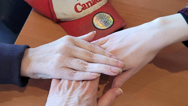 3 hands in a high five with a Canadian baseball hat below them.