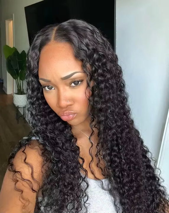 Long Burmese curly wig worn by model, HD 13x6 lace frontal, defined raw human hair curls cascading down length, 250% density