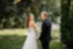 Beautiful Idaho wedding couple standing in a garden together. The bride is looking towards the camera as the groom looks at her.