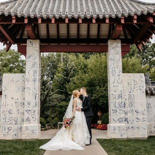 Wedding couple standing and kissing in a garden.