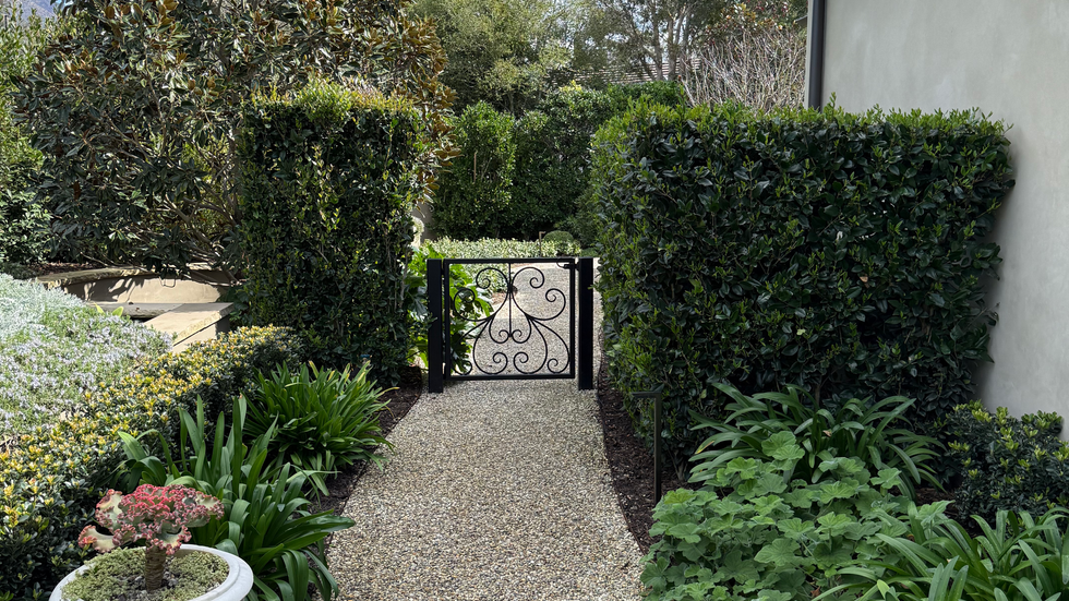Gravel path leading to ornamental iron garden gate