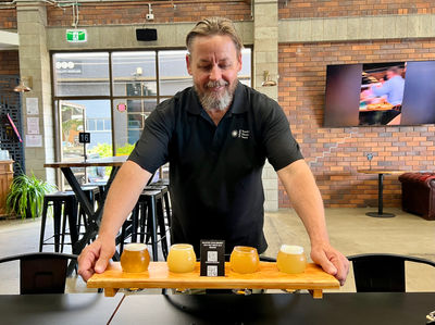 South East Discovery Tours host, PJ, placing a beer paddle on the table at Future Magic Brewing Co.