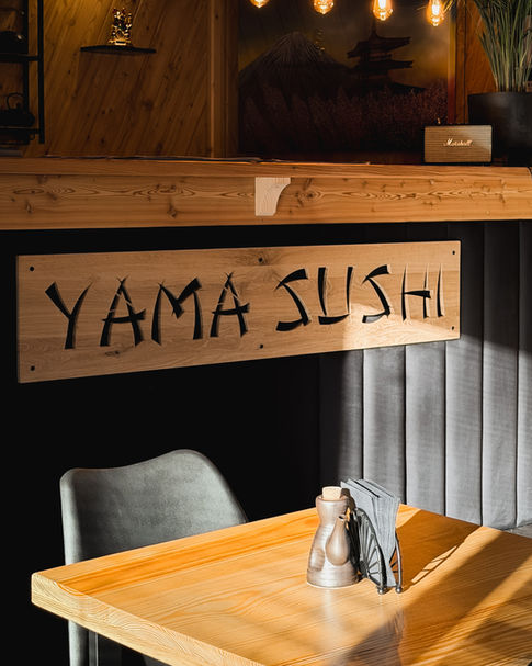 Przytulne wnętrze restauracji Yama Sushi w Kościelisku z drewnianym wystrojem i charakterystycznym logo.