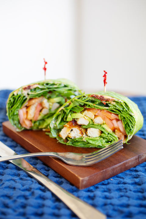 a grilled chicken wrap cut in half on a small cutting board