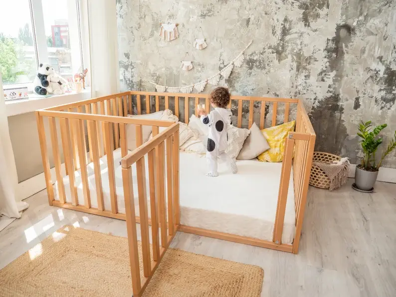 A toddler walking in his large, gated floor bed in his bedroom.