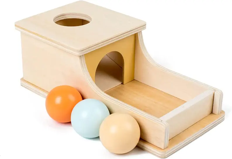 A wooden toy with 3 colored wooden balls next to it.