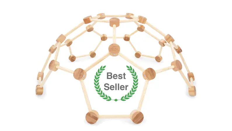 A wooden indoor climbing dome for toddlers on a white floor.