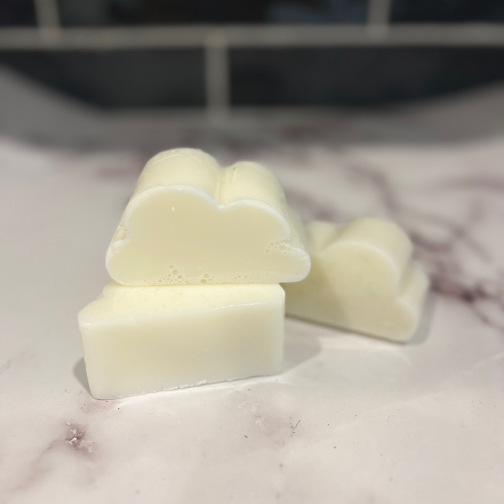 Three cloud-shaped soap bars on a marble countertop made from breastmilk and oatmeal.
