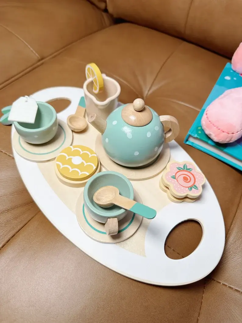 A blue and pink wooden tea set on a couch.