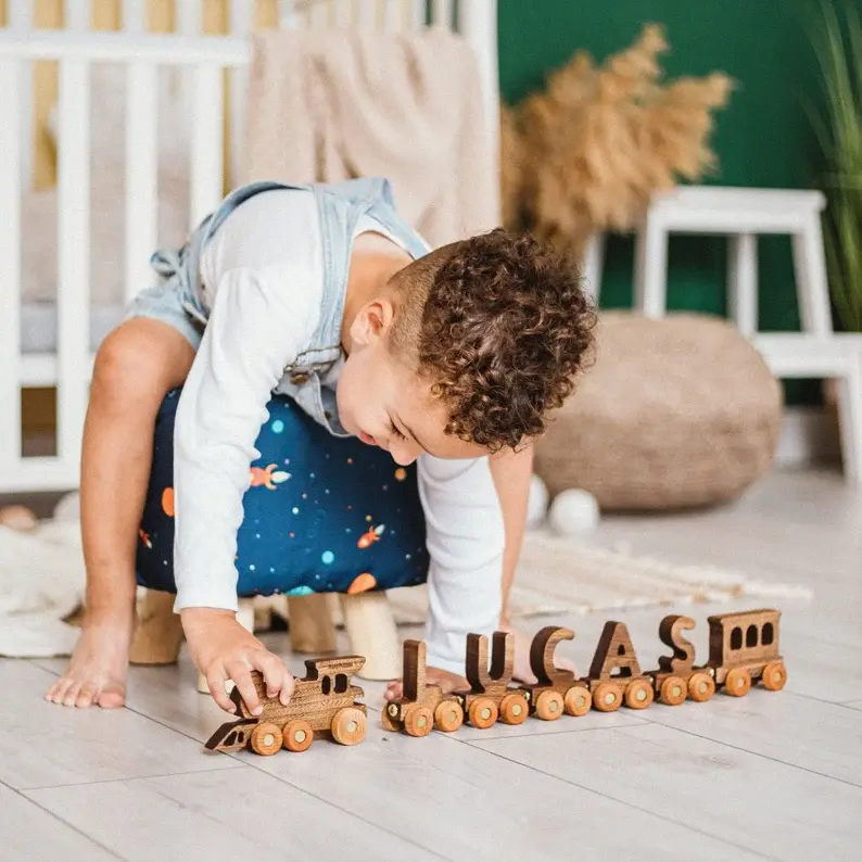 A little boy with curly hair playing with his personalized wooden train.