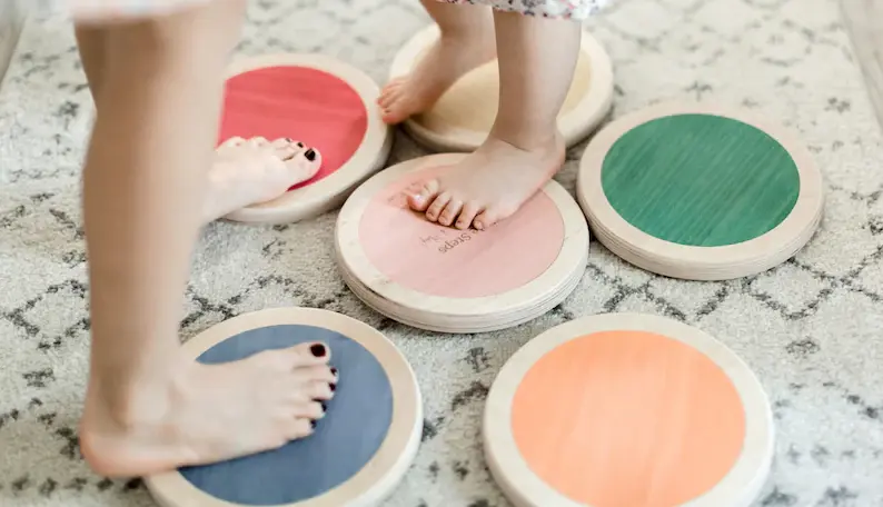 6 little wooden stepping pads with two kids playing on them in the living room.