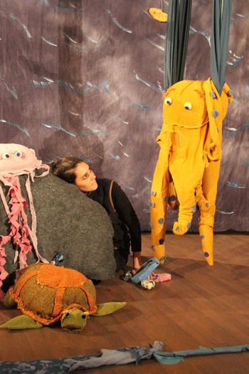 Schauspielerin mit orangener Stofffigur auf der Bühne des Horizont Theaters Köln