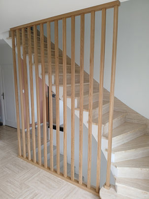 Claire-voie en chêne massif sur mesure à Ploemeur, sections 40x40 sur toute la hauteur, finition vernis mat incolore, servant de séparation entre deux niveaux d’escalier, création, fabrication et pose par Le Bail Agencement – menuisier, agenceur, ébéniste dans le Morbihan, lorient, ploemeur
