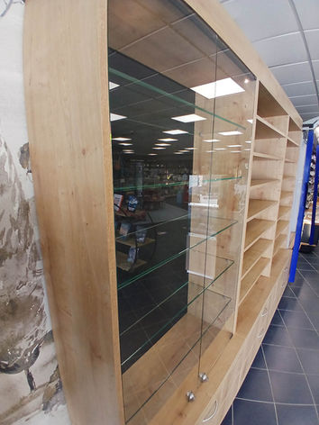 Meubles sur-mesure pour la Maison de la Presse à Clohars-Carnoët, avec présentoirs pour produits de vape, vitrine sécurisée et éclairage LED, création, montage et pose par Le Bail Agencement – menuisier, agenceur, ébéniste dans le Morbihan.