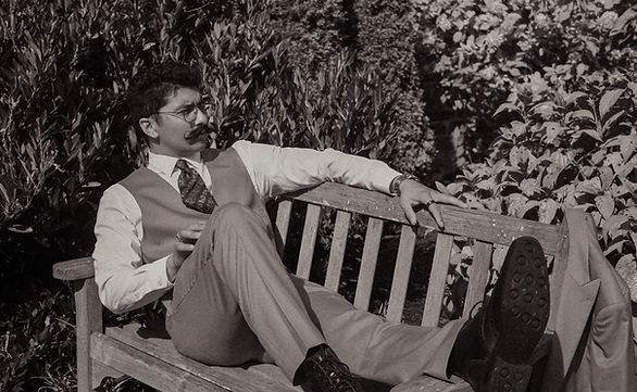A mustachioed man resting at a bench