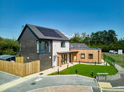 front of a house grey walls closest to us, then white then a wooden exterior extension