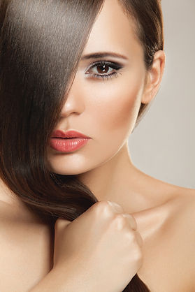 Woman with shiny, healthy hair and flawless makeup after professional salon hair treatment for smoothness and shine.