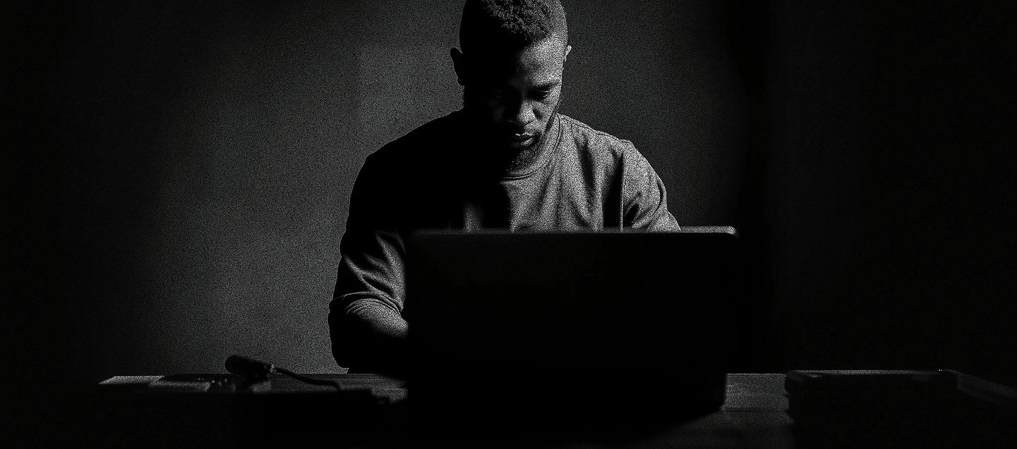 black man working on a laptop. A cinematic, hyper-detailed, monochrome image using a white