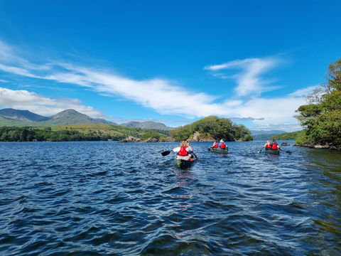 People canoeing with mountains in the background.