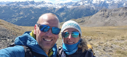 Man and Women smiling in the mountains wearing sunglasses.