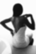 Black and white photo of black model posing from the back in white luxurious dress