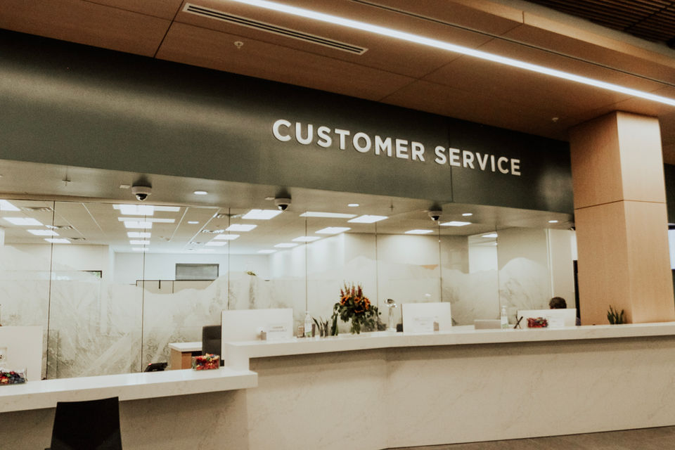 "Customer Service" desk sigange, silver lettering mounted to section above the glass seperator panes.