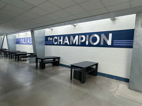 A large room with black tables and benches. Vinyl on the wall reads "the CHAMPION"