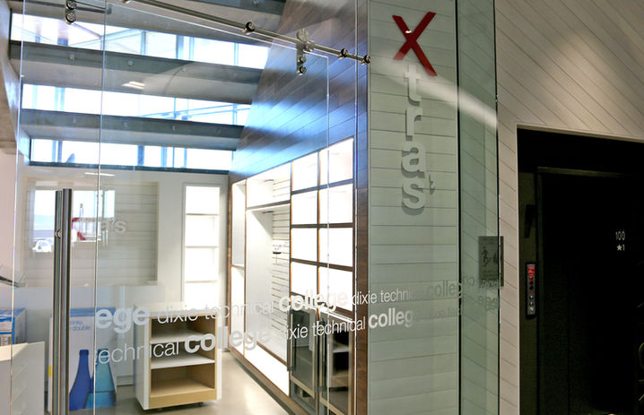 "Dixie Technical College" repeating vinyl decals across a glass pane, "Xtras" dimensional signage, designed with a red "X" and white "tras"