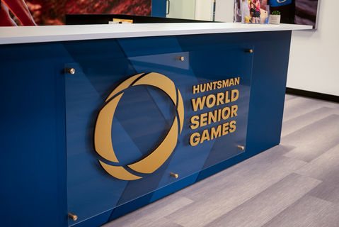 "Huntsman World Senior Games" plaque mounted to the front of a reception desk, made from gold anodized aluminum