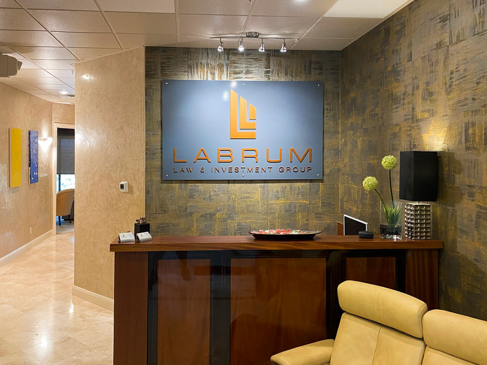 "Labrum Law and Investment Group" yellow lettering and logo against a grey acrylic plaque.