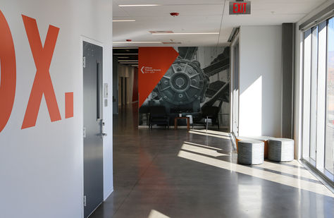 Red Wall graphics along a hallway, with directional signage at the end pointing left.