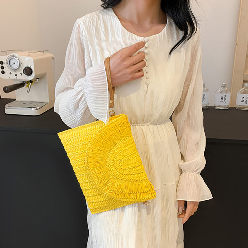 Thumbnail: Yellow handmade straw weave clutch bag being held by woman