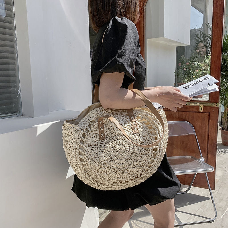 Thumbnail: Woman carrying a round handmade woven rattan straw bag.
