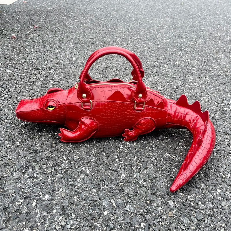 Thumbnail: Red crocodile-shaped luxury designer handbag on pavement